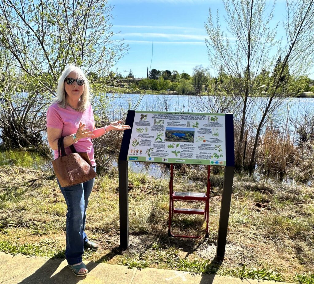 Artist Susan Lofthouse Meade and new Mary Lake plant sign. A. Henderson.