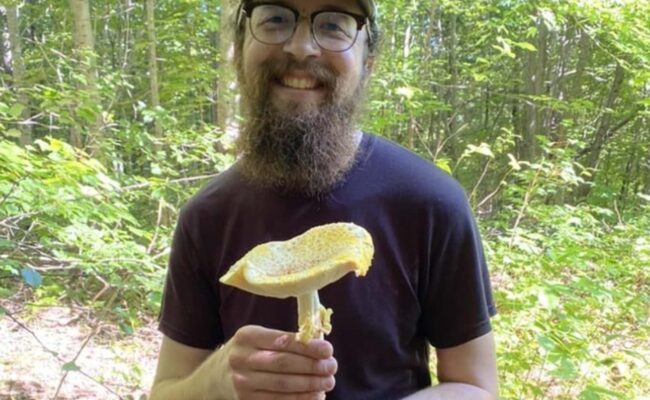 Josh Willems, previous scholarship awardee, with a yellow fly agaric in the White Mountains of New Hampshire. Photo provided by C. Willems.
